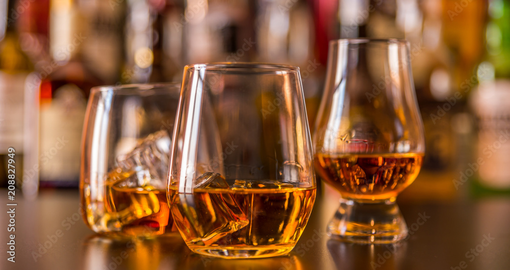 Scottish whisky in a glass with ice cubes, golden color whiskey Scottish whisky in a glass with ice cubes, golden color whiskey