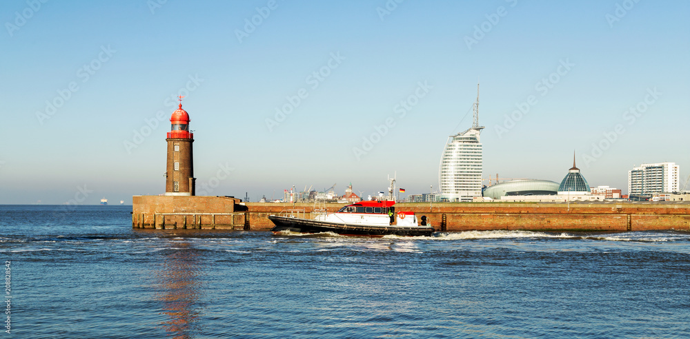 historischer Leuchtturm mit Skyline von Bremerhaven, Hafenstadt mit Mole und Schiff an der Nordseeküste