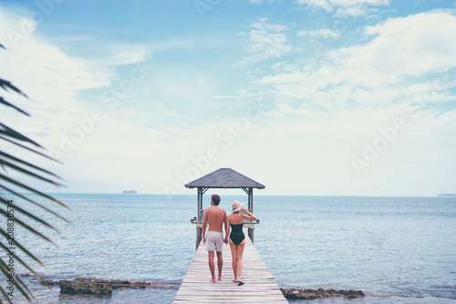 Honey moon on the sea shore. Back view of loving couple walking together on wooden pier.