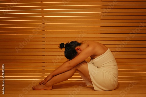 Girl in the Spa salon sitting on a bench in a hot sauna