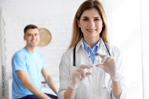 Doctor holding ampule with vaccine and syringe for patient in clinic