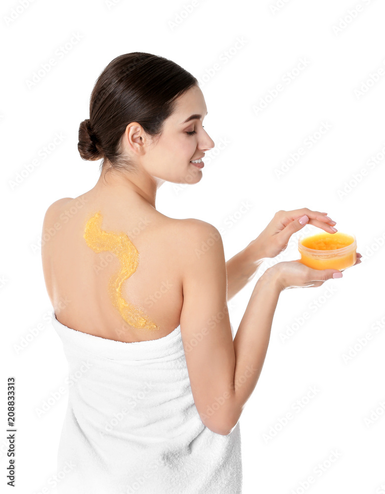 Young woman applying body scrub on white background