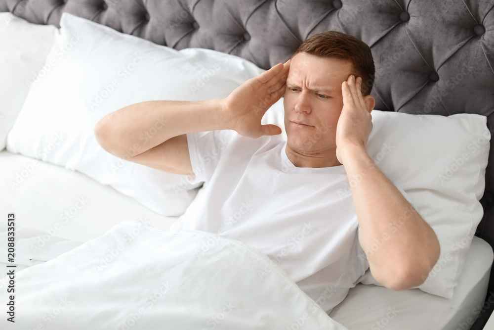 Young man with headache lying in bed Young man with headache lying in bed