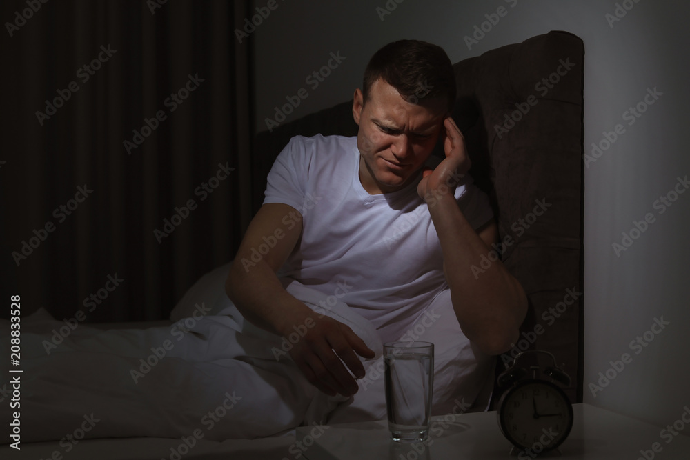 Fototapeta premium Young man with terrible headache want to take pill at night