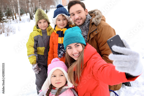 Happy family taking selfie in snowy park on winter vacation © Africa Studio