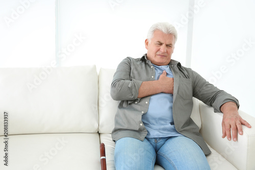 Senior man having heart attack on sofa