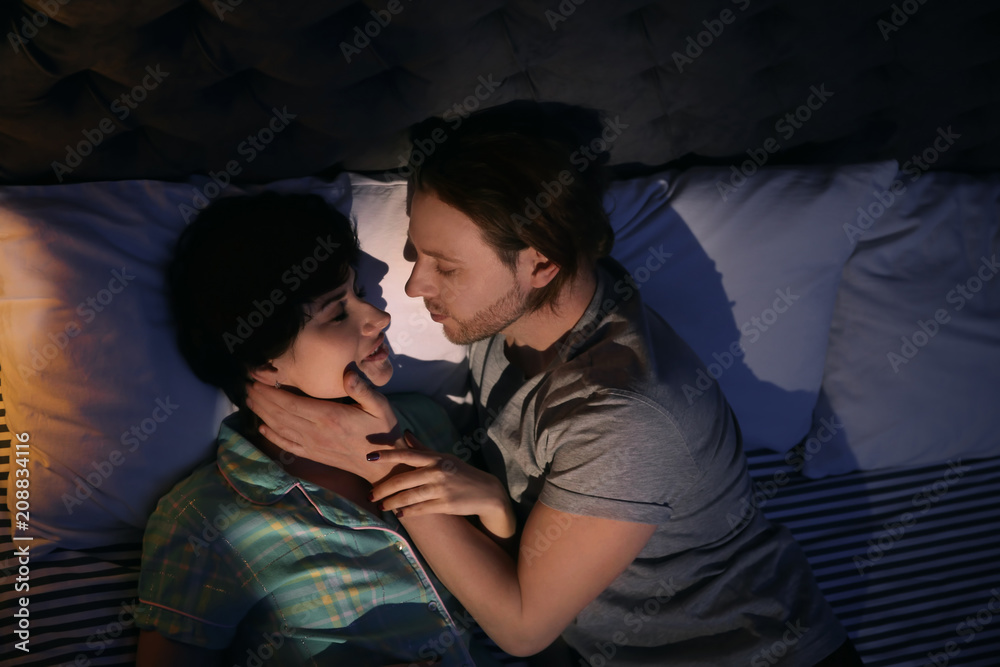Young couple in love on bed at night time Stock Photo | Adobe Stock