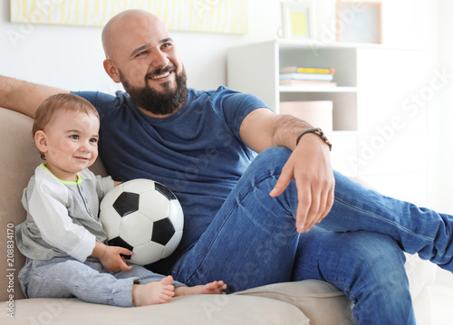 Dad and his son watching football at home