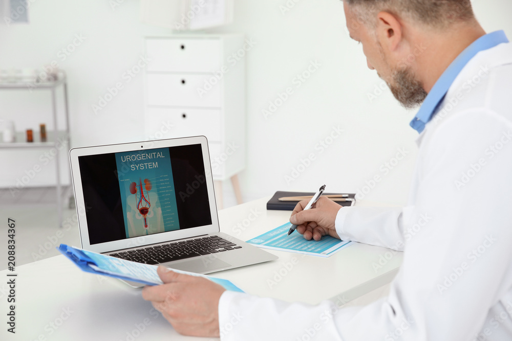 Mature urologist working at table in hospital Mature urologist working at table in hospital