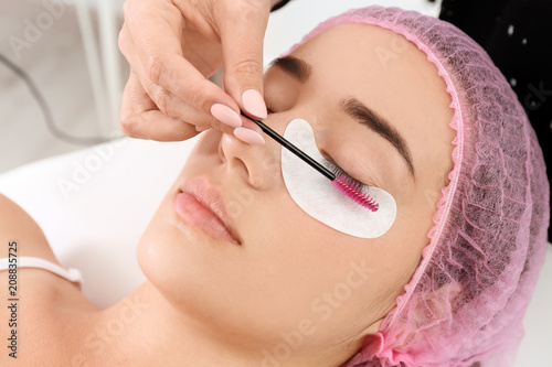 Young woman undergoing eyelash extensions procedure, closeup