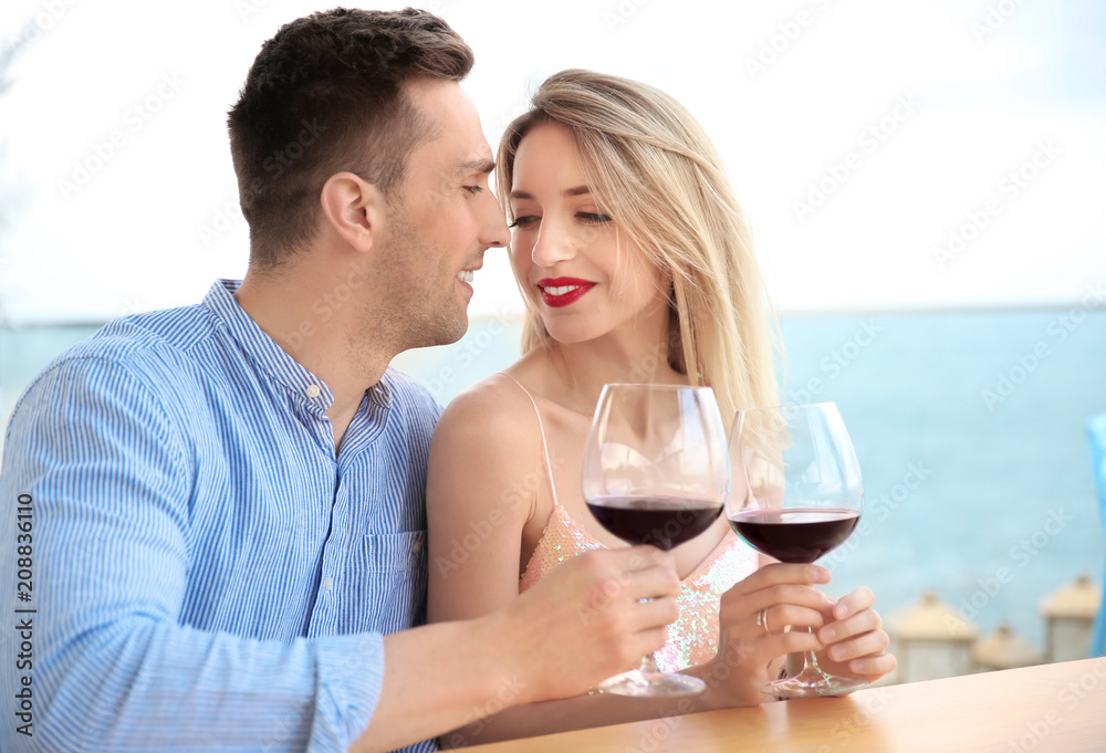Young romantic couple with glasses of red wine at table Young romantic couple with glasses of red wine at table