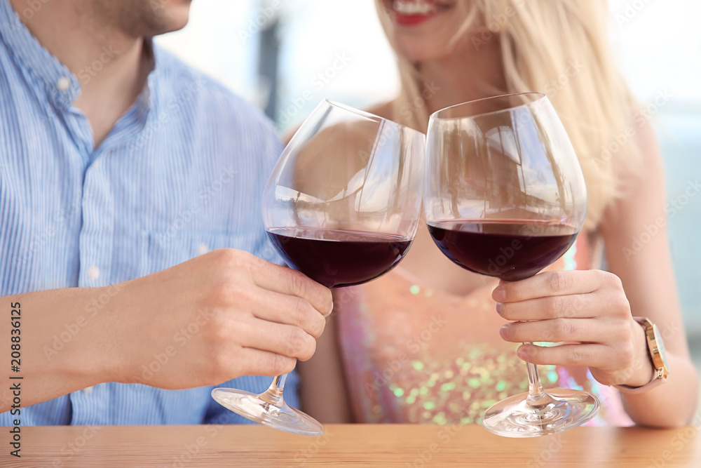 Young romantic couple with glasses of red wine at table