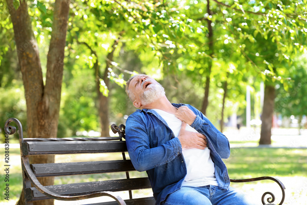Fototapeta premium Mature man having heart attack on bench in park