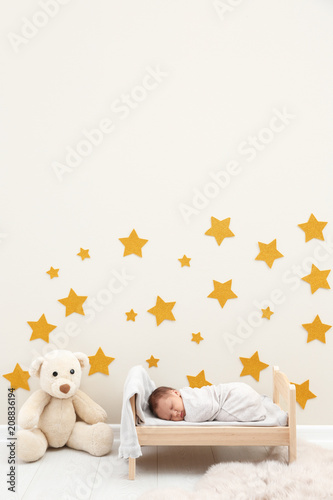 Adorable newborn baby sleeping in small bed