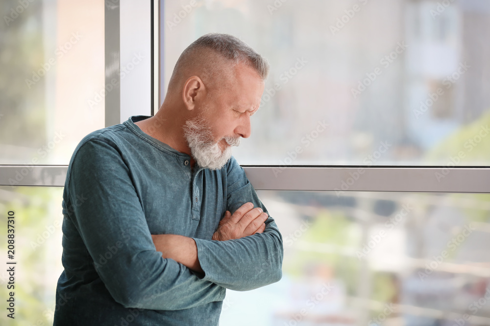 Naklejka premium Depressed senior man near window indoors