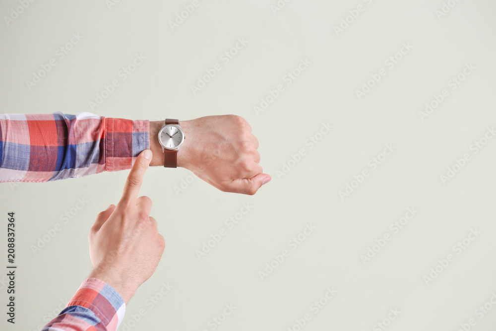 Fototapeta premium Young man with wristwatch on grey background. Time concept
