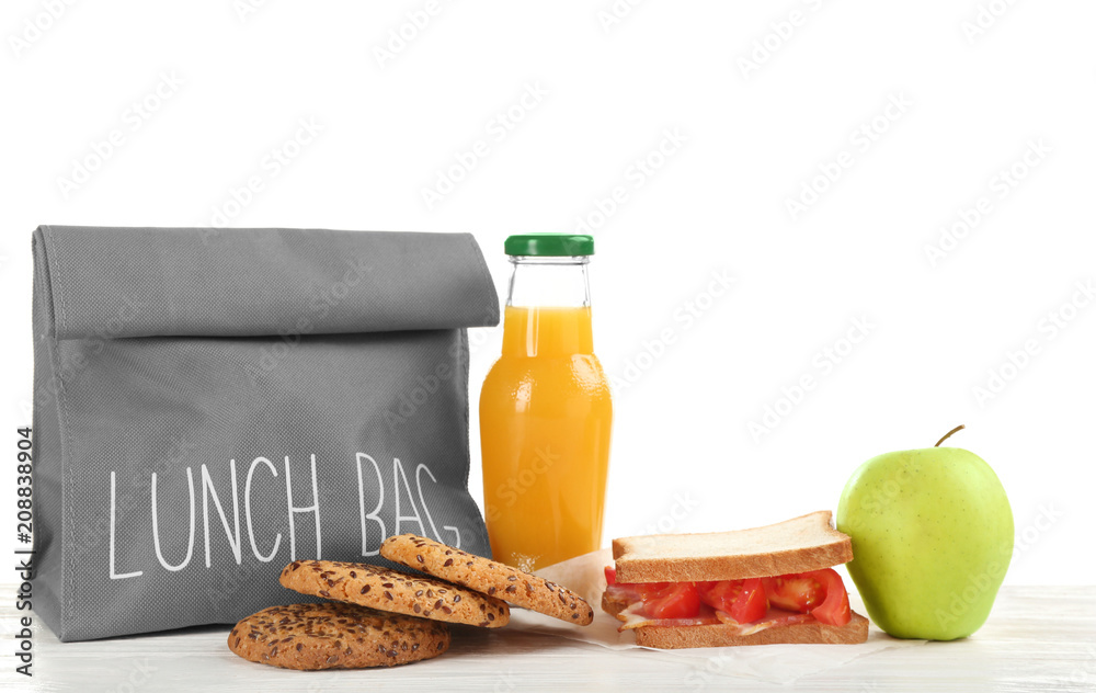 Lunch bag and appetizing food on table against white background