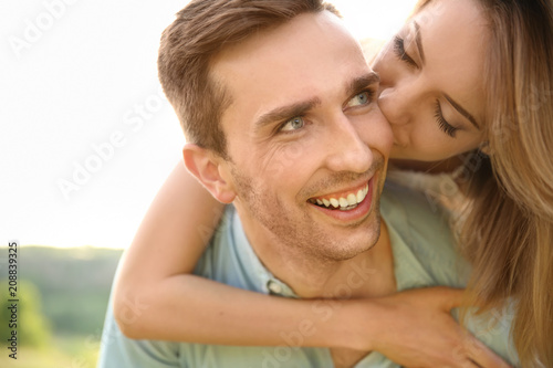 Cute young couple in love posing outdoors on sunny day