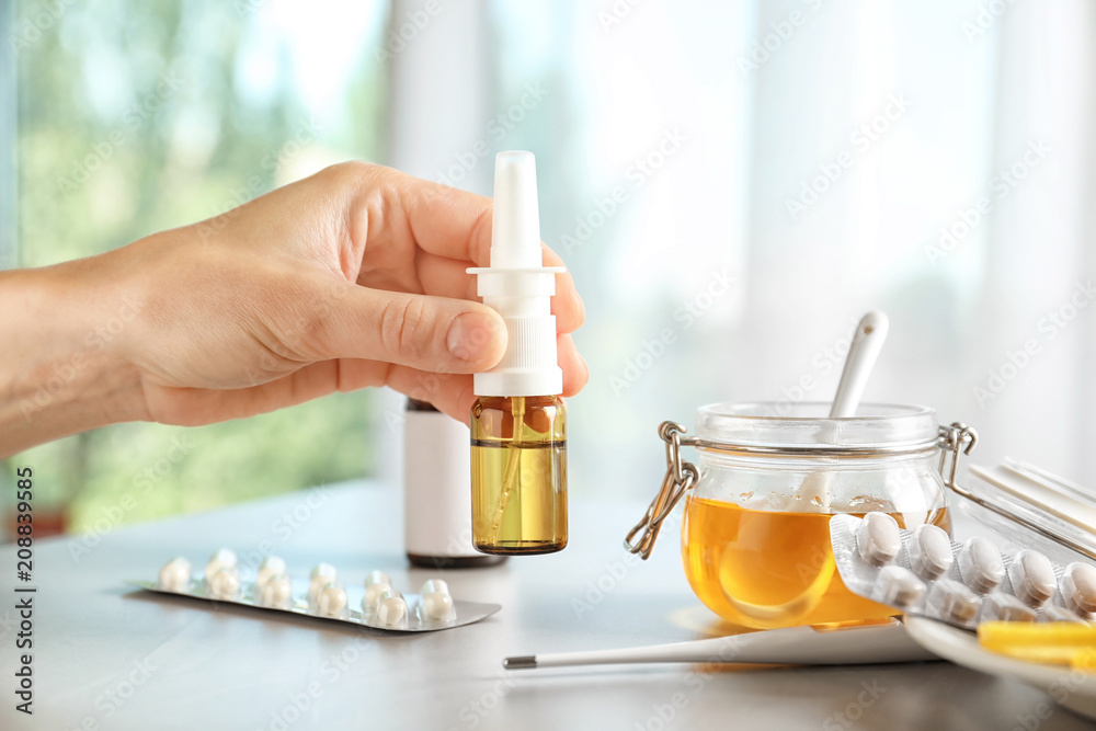 Woman holding remedy for cold over table Woman holding remedy for cold over table