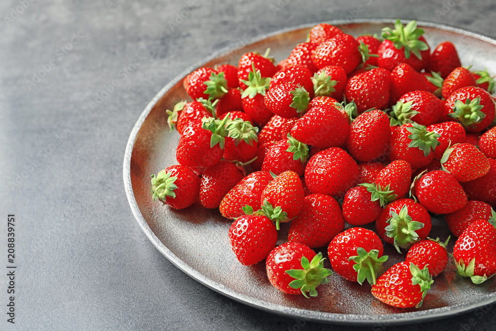 Plate with ripe strawberries on grey background Plate with ripe strawberries on grey background