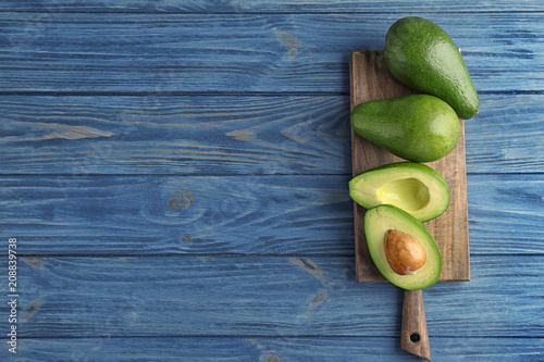 Board with ripe avocados on wooden background, top view