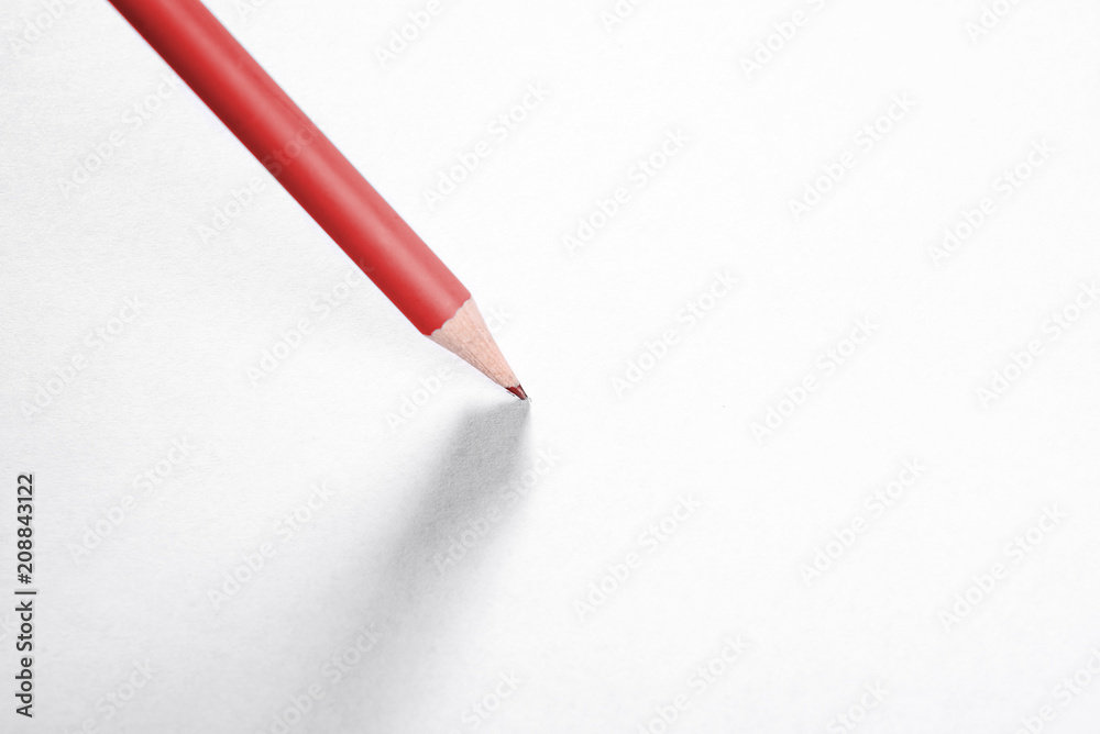 A simple red pencil with a shadow on a piece of white paper. A simple red pencil with a shadow on a piece of white paper.