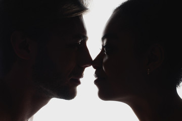 side view of silhouettes of interracial couple in love looking at each other
