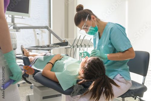 Orthodontist treating her patient in dental office photo