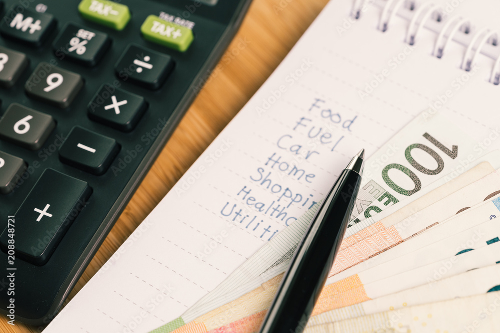 Payment and expense calculation concept, pen on list numbers of expenses or cost on small paper white notepad with Euro banknotes and calculator on table Payment and expense calculation concept, pen on list numbers of expenses or cost on small paper white notepad with Euro banknotes and calculator on table