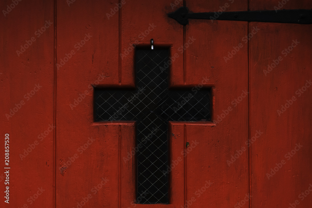 red door with a small window in the form of a cross and a black door hinge