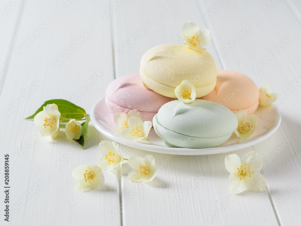 Colorful macaroons with Jasmine flowers on a white wooden table.