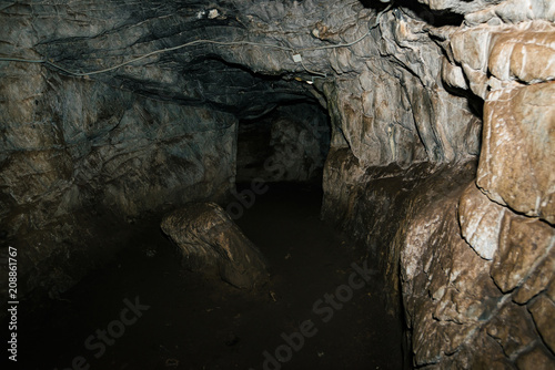 Beautiful cave. View from inside dark dungeon. Textured walls of cave. Background image of underground tunnel. Dampness inside cave. Lighting inside cave for excursions.