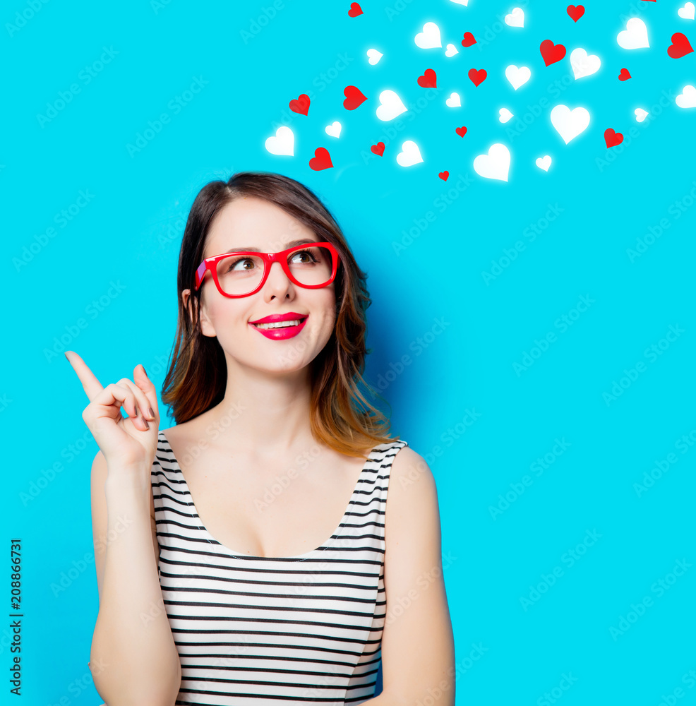 portrait of beautiful smiling young woman in glasses on the wonderful blue studio background and abstract hearts portrait of beautiful smiling young woman in glasses on the wonderful blue studio background and abstract hearts