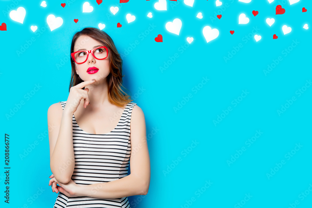 portrait of beautiful young woman in glasses on the wonderful blue studio background and abstract hearts