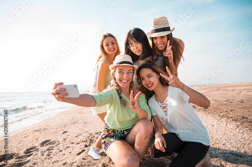 Happy multiracial young people making a selfie at the beach while they are in a summer party. Friends and holiday concept