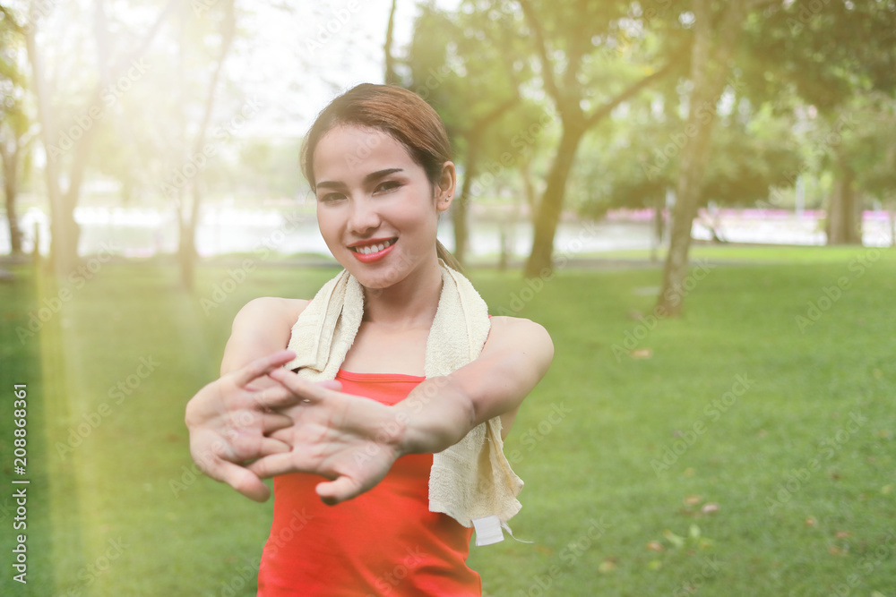 Young Asian woman stretching her hands before run in park with sunshine effect. Fitness and exercise concept. Young Asian woman stretching her hands before run in park with sunshine effect. Fitness and exercise concept.