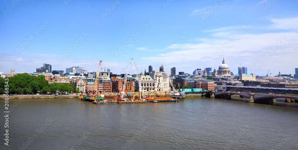 Panorama of The City of London overlooking The River Thames with various iconic buildings against a blue cloudy sky