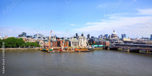 Panorama of The City of London overlooking The River Thames with various iconic buildings against a blue cloudy sky