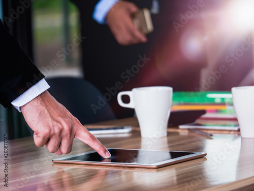 Close up of hand of businessman point finger on tablet screen display on meeting table
