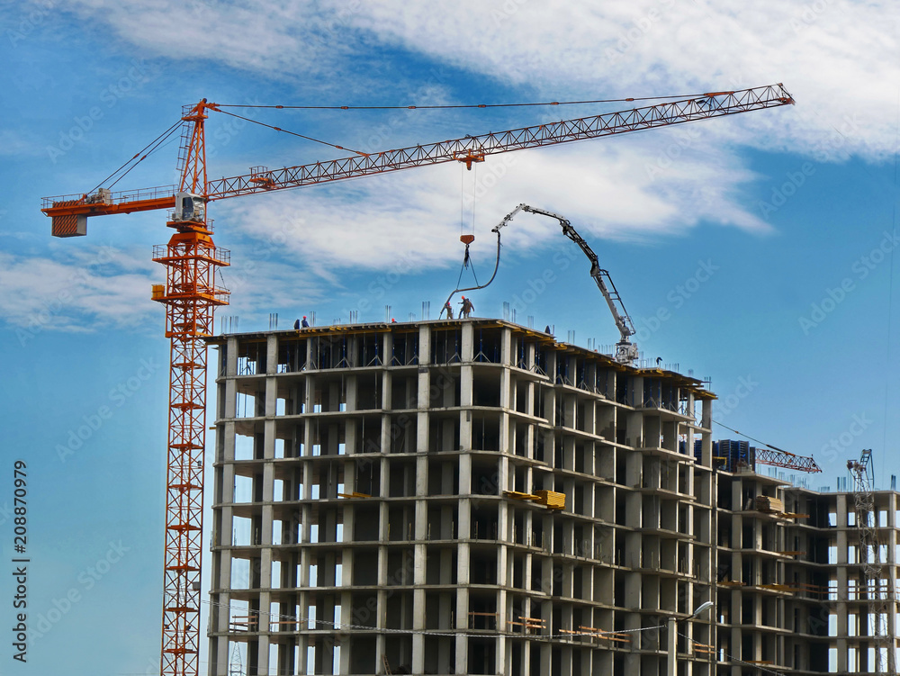 Construction crane and concrete building under construction against blue sky. Construction site. Construction crane and concrete building under construction against blue sky. Construction site.