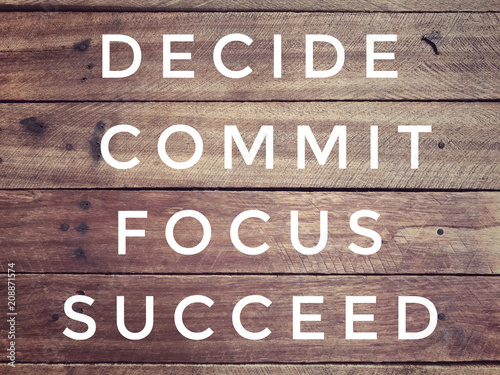 Motivational and inspirational quote - ‘ Decide, commit, focus, succeed’ on a wooden wall. With vintage styled background.