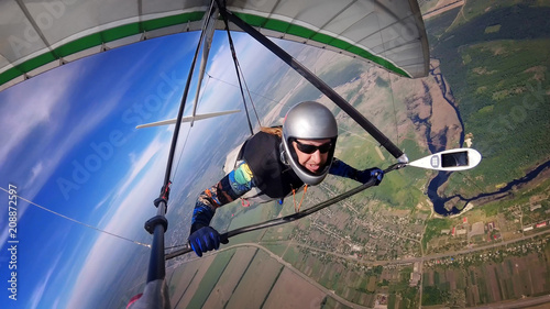 Brave hang glider pilot soar high over town and river. photo