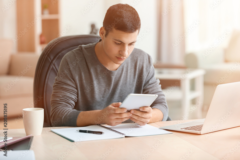 Young man working with tablet PC in home office