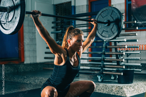 Obraz na plátně Cross training. Female athlete lifting heavy barbells