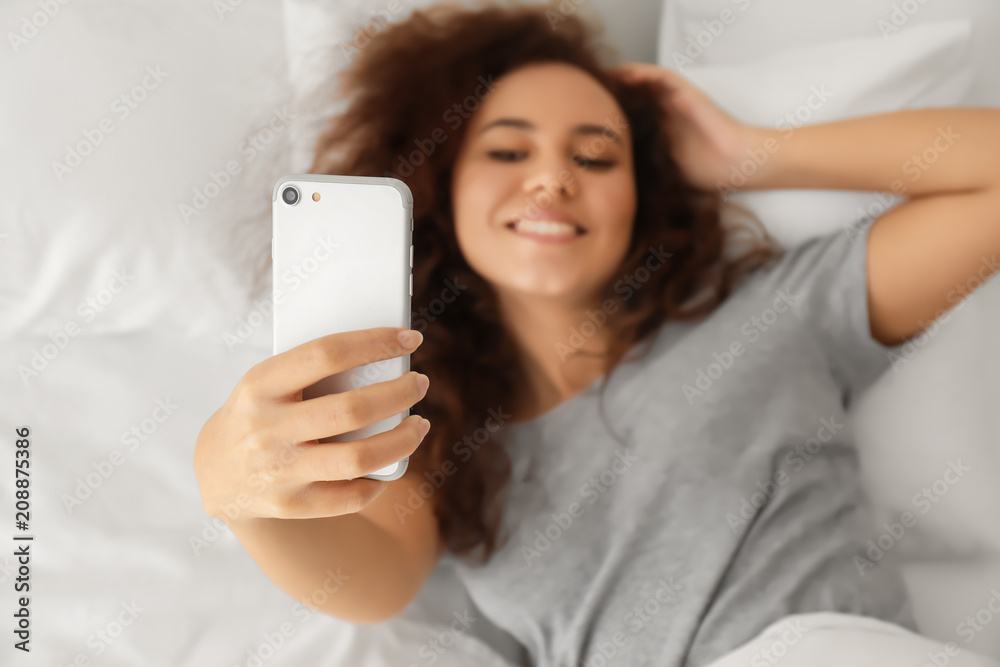 Morning of young African-American woman taking selfie in bed Morning of young African-American woman taking selfie in bed