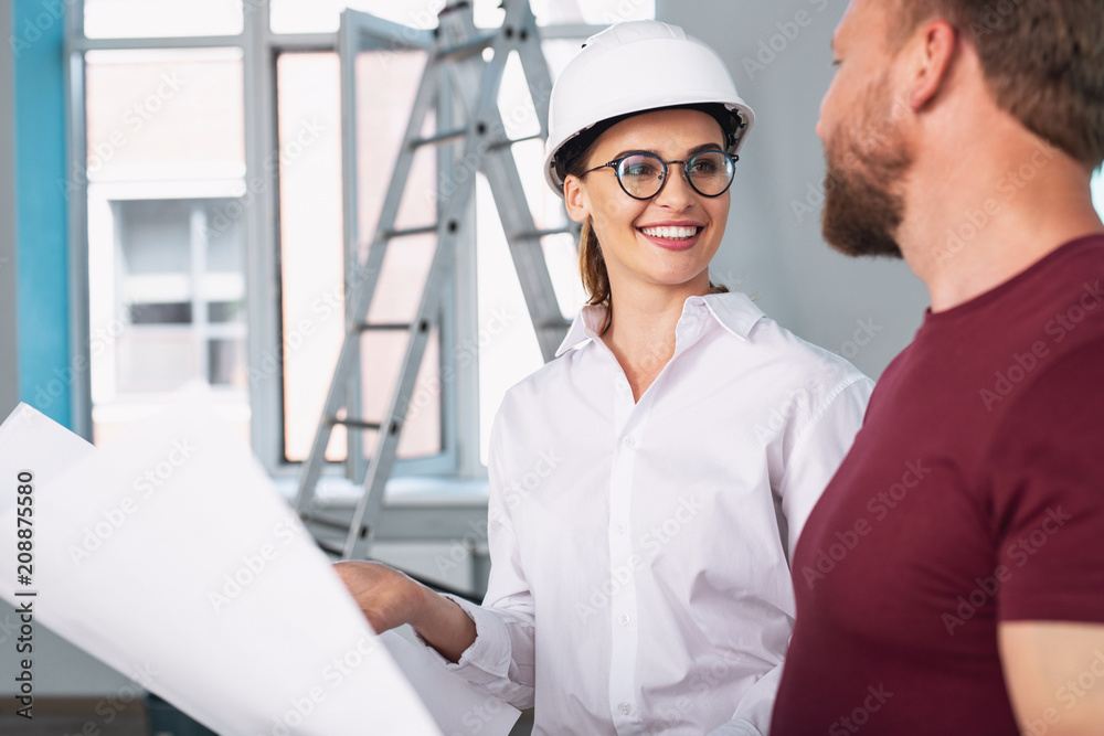 New design. Nice joyful woman holding the sketch and talking with a man New design. Nice joyful woman holding the sketch and talking with a man
