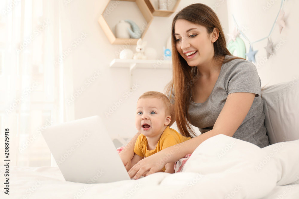 Young mother with baby working on bed at home Young mother with baby working on bed at home