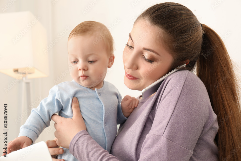 Young mother holding baby while working at home Young mother holding baby while working at home