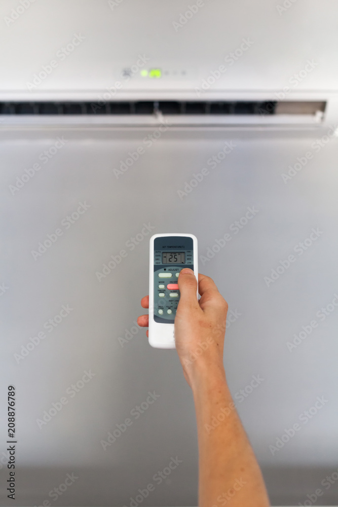 Hand using a remote control to activating air conditioning Hand using a remote control to activating air conditioning
