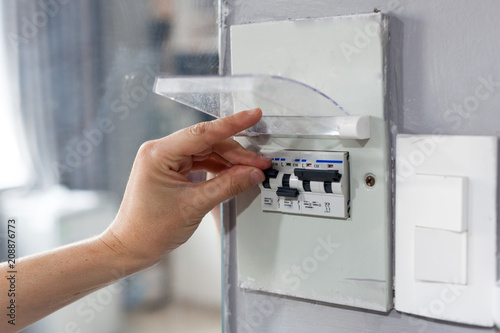 Woman hand  turning off fuse box in the house